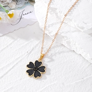 Collier en or élégant avec pendentif trèfle noir sur un présentoir en marbre