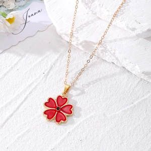 Collier chaîne dorée à la mode avec pendentif trèfle à cinq pétales rouges sur fond pierre