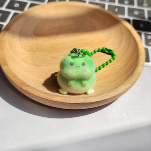 Gros plan d'un adorable porte-clés grenouille en peluche verte sur un plateau