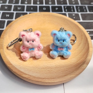 Dettaglio di portachiavi a forma di orsetto rosa e blu con ganci su vassoio in legno