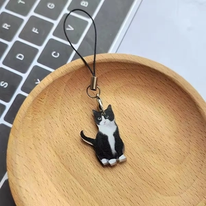 Portachiavi gatto bianco e nero in acrilico con cinturino nero in una ciotola di legno