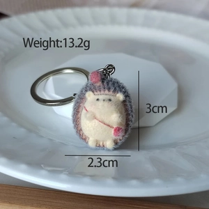 Macro detail of a small wool felt hedgehog keychain with dimensions 3cm x 2.3cm