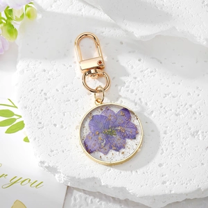 Close-up of golden resin keychain featuring a real purple pansy flower and gold leaf details