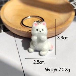 Détail d'un porte-clés chaton floqué blanc avec touches roses sur un plateau en bois clair