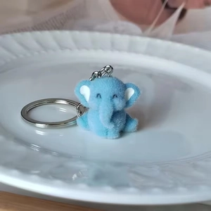 Cute light blue plush elephant keychain with silver ring on a white ceramic plate