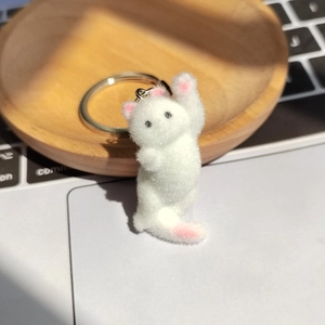 Détail d'un porte-clés chaton blanc floqué avec un anneau métallique argenté sur un bureau