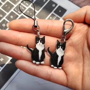Dettaglio di ciondoli in acrilico gatto bianco e nero con moschettone e laccetto telefono