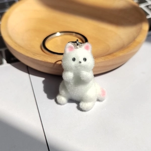 Gros plan d'un porte-clés chaton blanc floqué avec un anneau en métal sur bois naturel