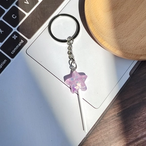 Macro detail of purple resin star lollipop keychain with glitter on laptop keyboard