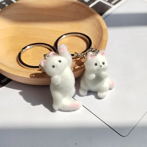 Gros plan détaillé de porte-clés chat floqués blancs avec détails roses sur plateau