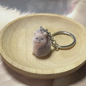 Cute pink and grey plush hedgehog keychain on a soft fur mat with wooden tray decoration