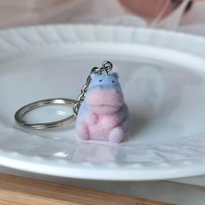 Cute pink and blue gradient flocked hippo keychain pendant on a white ceramic plate