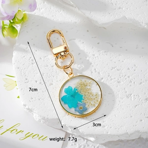 Vue à plat d'un porte-clés en résine avec de vraies fleurs séchées bleues et métal doré