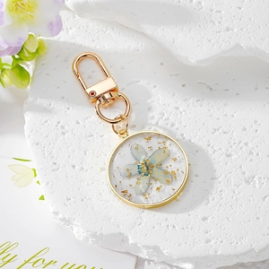 Porte-clés artisanal en résine avec fleur séchée bleue et détails en feuille d'or