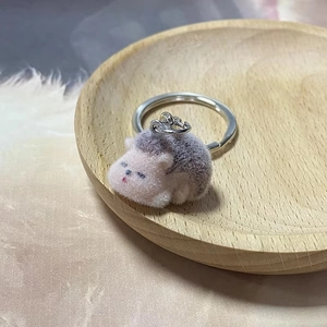 Detailed view of a cute pink plush hedgehog keychain on a wooden tray background