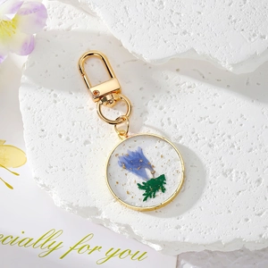 Handmade gold pendant keychain with blue dried flowers and gold foil in clear resin