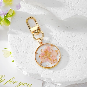 Vue détaillée d'un porte-clés en résine avec véritable fleur séchée rose et feuilles d'or