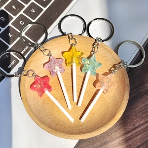 Close-up of colorful resin star lollipop keychains with glitter on a wooden tray