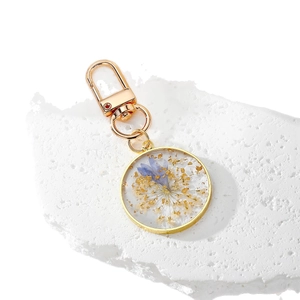 Clear resin round keychain with real blue dried flowers and golden foil accents