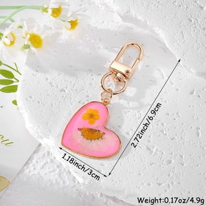 Macro shot of heart-shaped resin keychain with dried flowers showing 6.9cm size detail