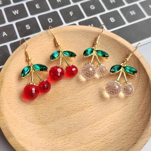 Detailed view of resin cherry drop earrings in red and pink with faceted beads