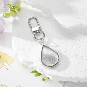 Portachiavi a goccia con fiori secchi blu e foglia d'oro su pietra bianca