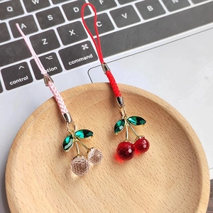 Detail of red and pink resin cherry pendants with woven straps and metal clasps