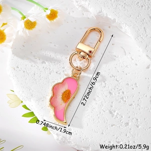 Detailed macro of pink daisy flower resin wing keychain with gold-plated spring D-ring clasp