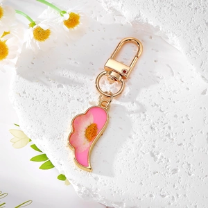 Close-up of golden keychain featuring real dried daisy in pink resin on stone