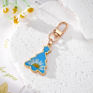 Détail d'un porte-clés sapin de Noël bleu avec marguerite sur pierre décorative