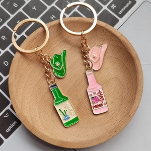 Detailaufnahme von Schlüsselanhängern mit Cowboyhut und Soju-Flasche auf Holztablett