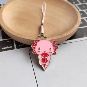 Close-up of pink axolotl enamel keychain charm with woven strap on wooden tray