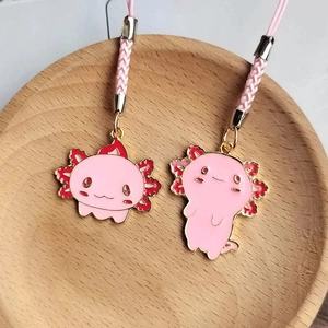 Close-up of cute pink axolotl alloy charms with woven ropes on a wooden tray