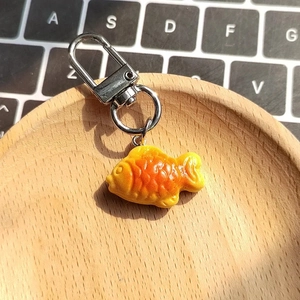 Creative resin taiyaki fish biscuit keychain on a wooden tray with a laptop background