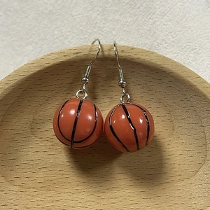 3D basketball-shaped resin hook earrings in orange color on a wooden tray