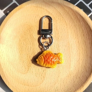 Macro detail of a resin Taiyaki fish charm with realistic baked texture on wooden tray