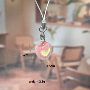 Close-up of pink flocked apple keychain with yellow heart pattern and metal lobster clasp
