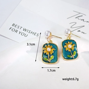 Detail of vintage enamel earrings with yellow daisy pattern and faux pearl accents