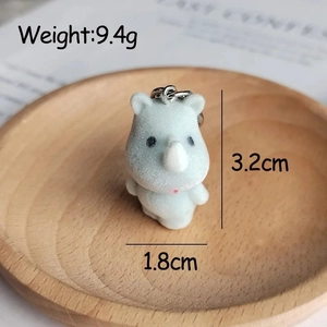 Detailed macro view showing a cute 3.2cm plush rhino keychain on a wooden base
