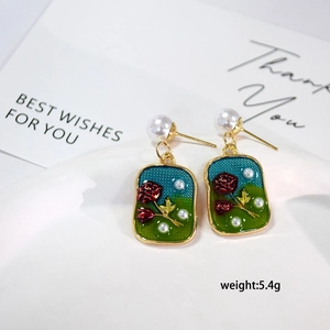 Detailed macro view of vintage enamel earring with rose pattern and small pearls