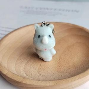 Cute gray flocked rhino keychain with silver metal ring on a wooden tray
