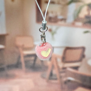 Close-up of pink flocked apple keychain with a yellow heart and silver lobster clasp