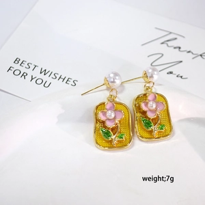 Detail of French enamel earrings with white pearls and floral pattern in gold finish