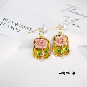 Detail of French vintage earrings featuring pink enamel floral motifs and white pearls