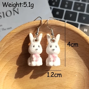 Close-up of white flocked rabbit earrings with pink flower detail and metal hooks