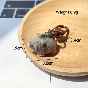 Macro detail of a miniature flocked wild boar keychain with a brown plastic clasp