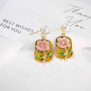 Detailed close-up of retro floral enamel earrings with white pearls and gold metal