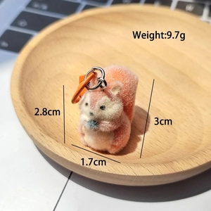 Close-up of cute flocked squirrel keychain with metal ring on light wood tray