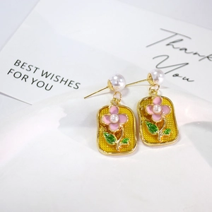Detail of French vintage pearl earrings with pink enamel flower on gold irregular frame