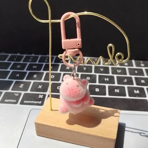 Detail of pink flocked pig keychain with matte D-ring on gold smile metal stand